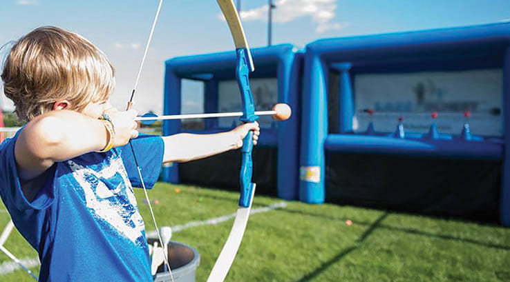 A boy aiming his bow and arrow in archery