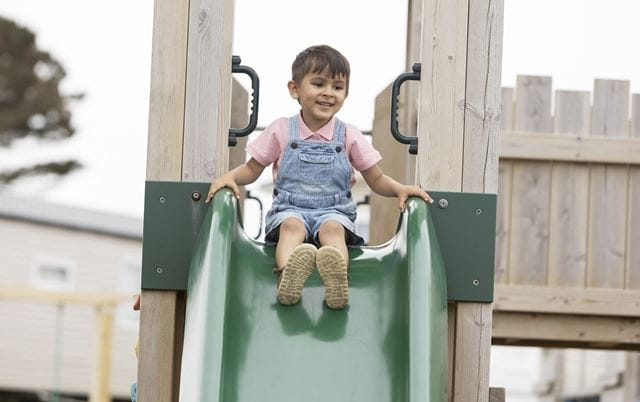 child going down a slide in outdoor play area
