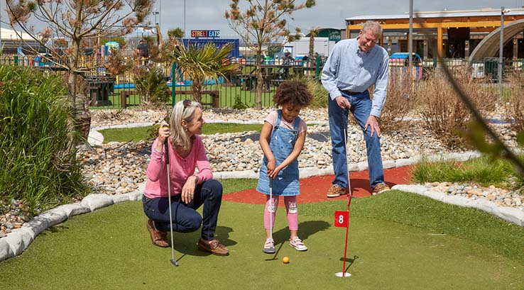 Grandparents and a little girl playing crazy golf at Camber Sands
