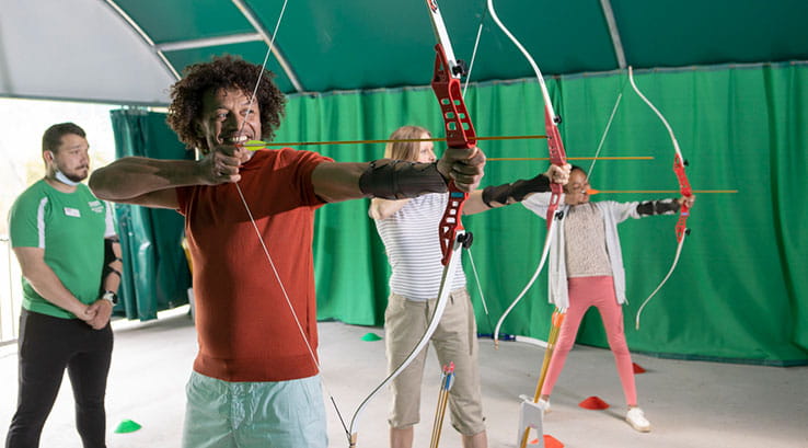 three people being taught archery