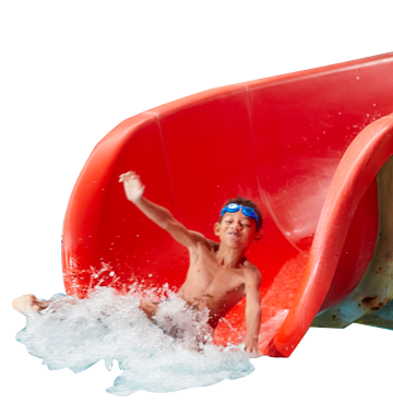 Young boy wearing blue goggles on head sliding down a red slide into a swimming pool