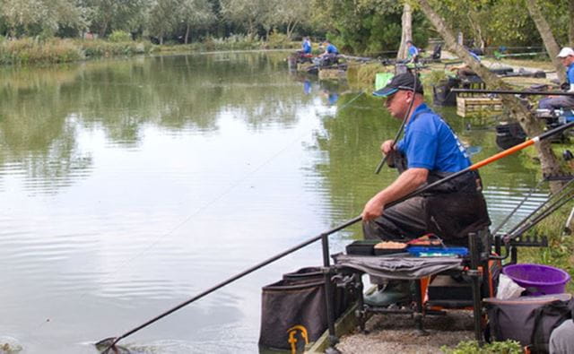 a fisherman sat on the bank of a lake whilst match fishing