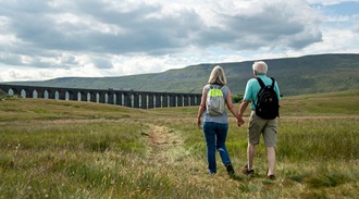 a couple holding hands walking towards a viaduct