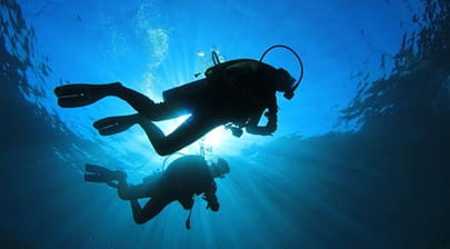 Two silhouetted divers under water