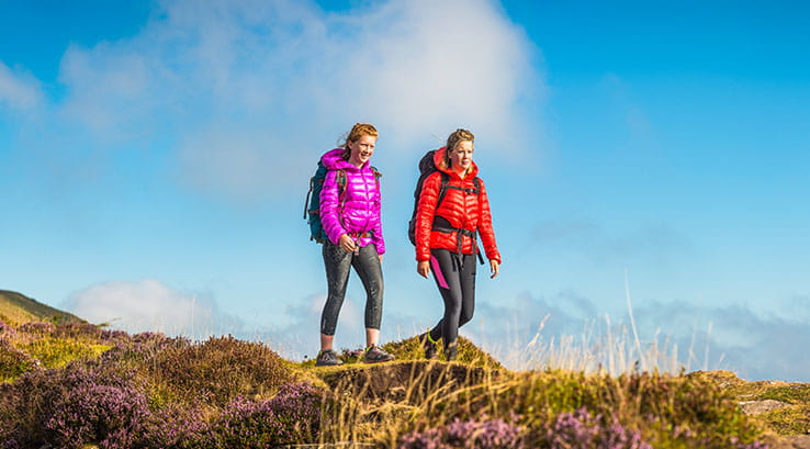 A mother and teenage daughter walking over the grassy Brecon Beacons in Wales