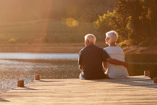 older couple sitting by a lake together