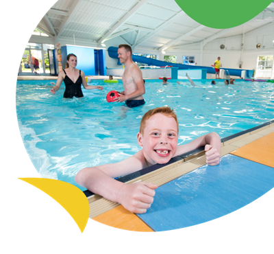 A boy smiling in the indoor swimming pool at Brynowen Holiday Park