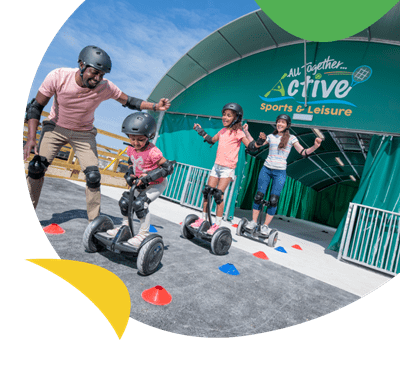 A family on hoverboards outside the activities hub at Cayton Bay Holiday Park