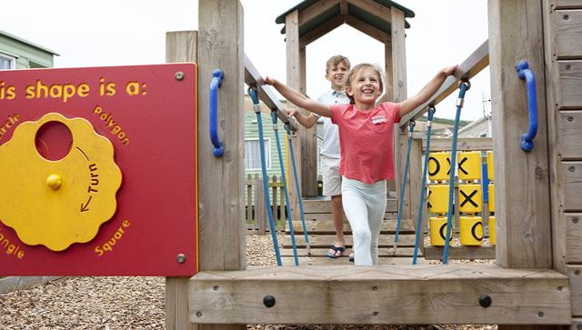 Two children  on the outdoor adventure playground at Challaborough Bay Holiday Park