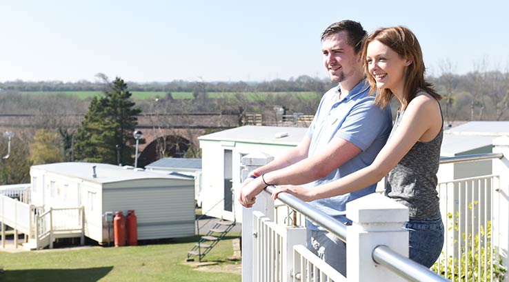 A couple enjoying the view from their lodge veranda at Crimdon Dene Holiday Park