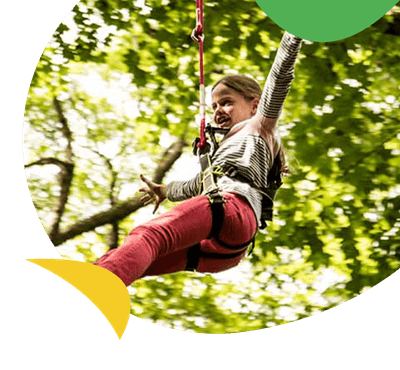 A girl swinging through the trees at the Treetop Trek atttraction
