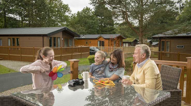 A family relaxing on their lodge veranda at Gatebeck Holiday Park