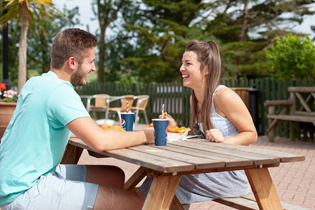 couple sat enjoying drinks at a picnic bench