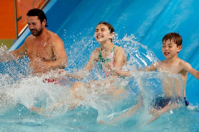 A family sliding down the waterslide into the indoor swimming pool
