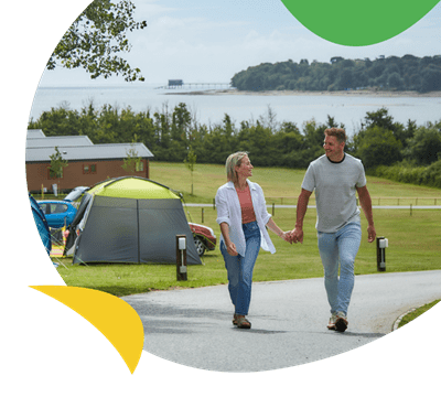 tA couple walking past the touring and camping site at Nodes Point Holiday Park
