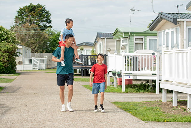 Father and kids walking past holiday accommodation at Romney Sands Holiday Park