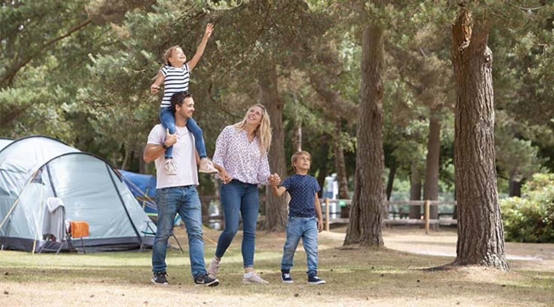 family walking through trees next to a tent