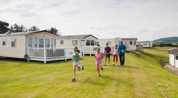 A family walking across the grass by the lodges at Southerness Holiday Park