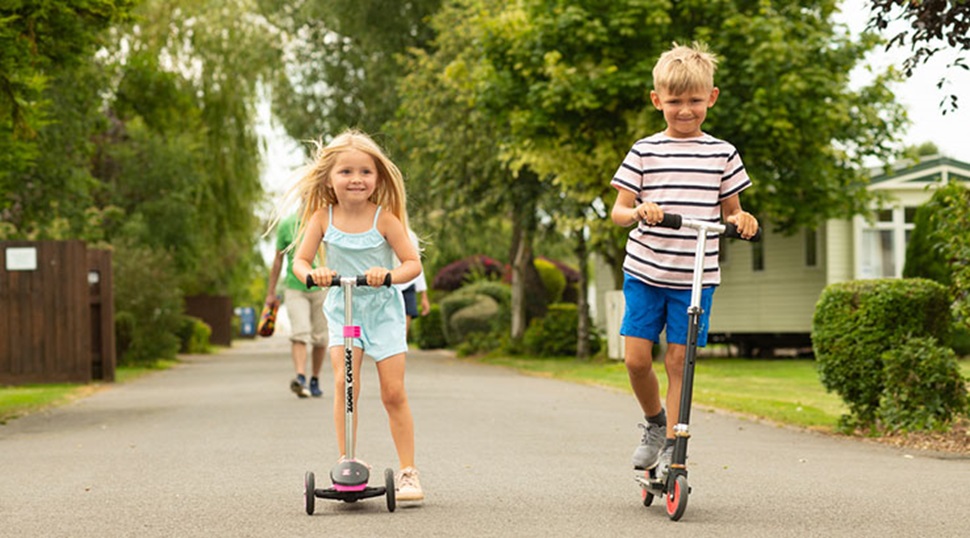 two children on scooters next to caravans