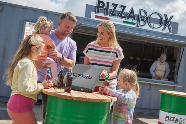 family eating a takeaway pizza outside the pizza box van