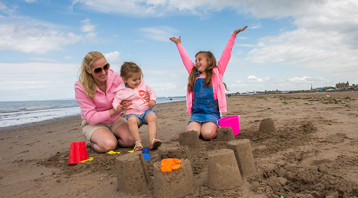 A family building sandcastles at Ayr Beach