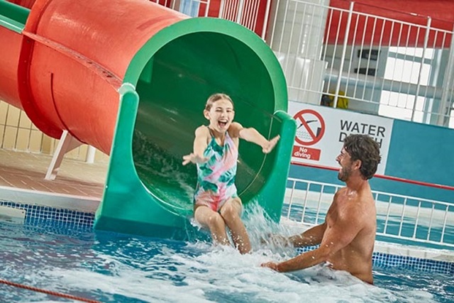 A girl sliding down the flume to her dad in the indoor pool at Thorness Bay