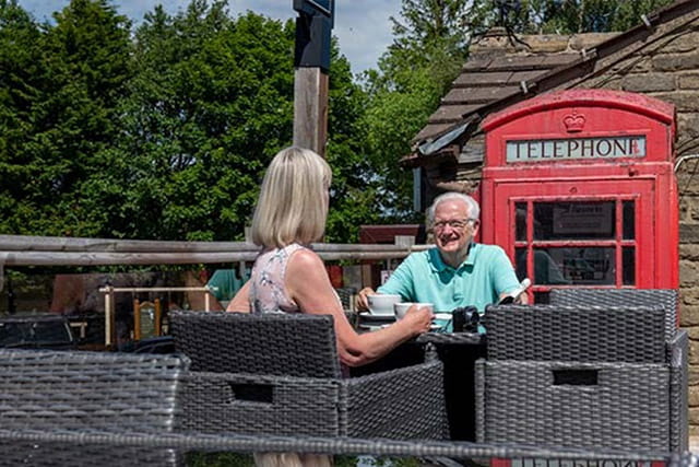 A couple enjoying refreshments on the outdoor patio at Todber Valley
