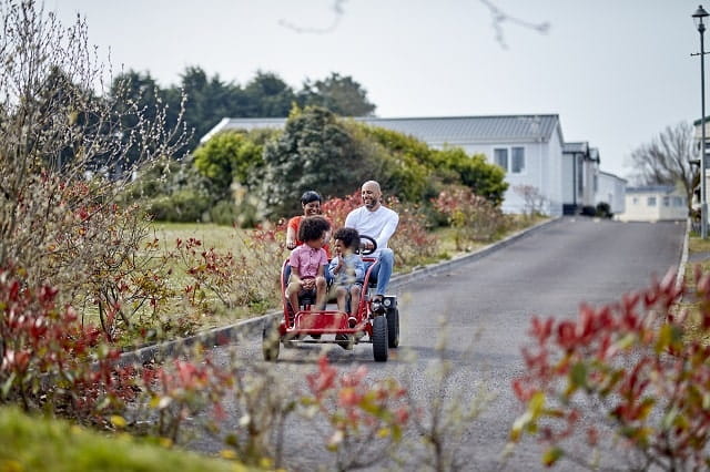 A family on a kart riding past holiday accommodation at Trecco Bay Holiday Park