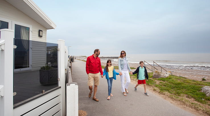A family walking along hand in hand by the caravans overlooking Trecco Bay beach