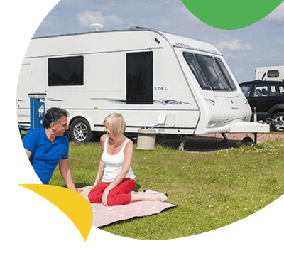 A family relaxing on the grass on the touring field at Ty Mawr Holiday Park