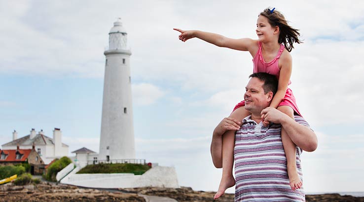 A father with his daughter on his shoulders by St. Mary's Lighthouse