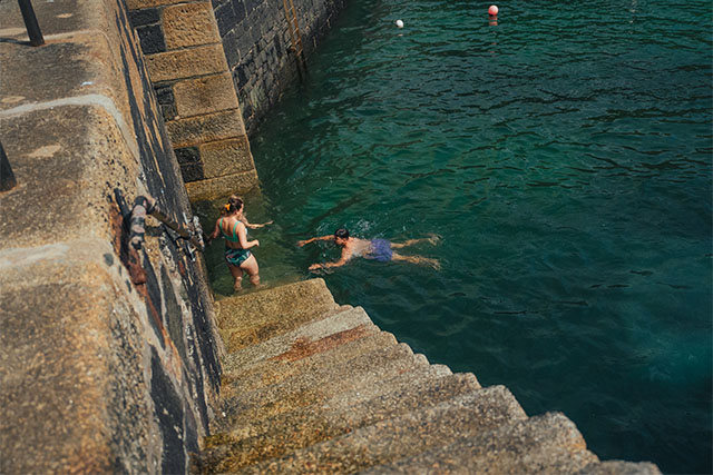A couple swimming in the sea off some steps 