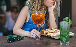 A woman drinking a cocktail with a pizza