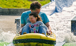 A father and daughter bracing themselves with excitement on a water ride at Camel Creek in Cornwall