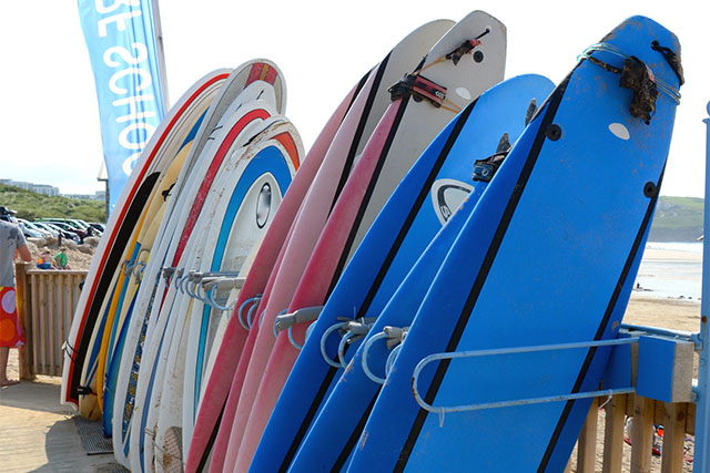 A row of surfboards stacked up on the boardwalk by Fistral Beach in Cornwall