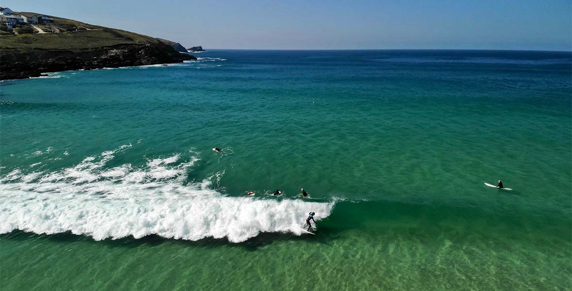 Surfers lining up to catch waves at Fistral Beach in Cornwall