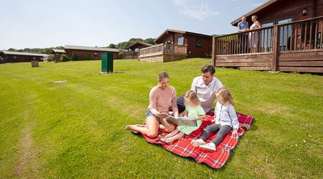 Family having a picnic on the grass outside a holiday lodge
