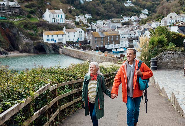 A couple walking through a Cornish fishing village in autumn