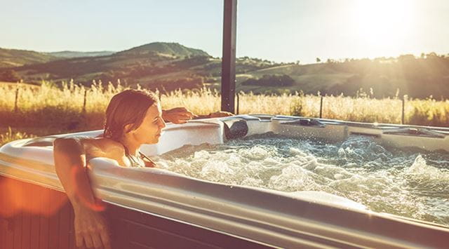 woman relaxing in a hot tub at sunset