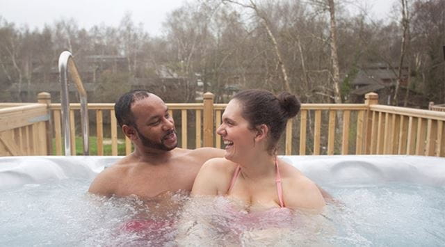 a couple relaxing in a hot tub with trees in the background