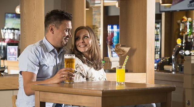 A couple enjoying a drink at the bar at a Parkdean Resorts Holiday Park