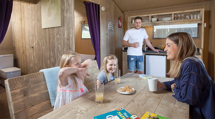 Family around the dining table in glamping tent