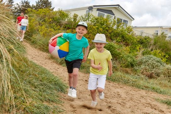 kids walking down sand dunes with a beach ball