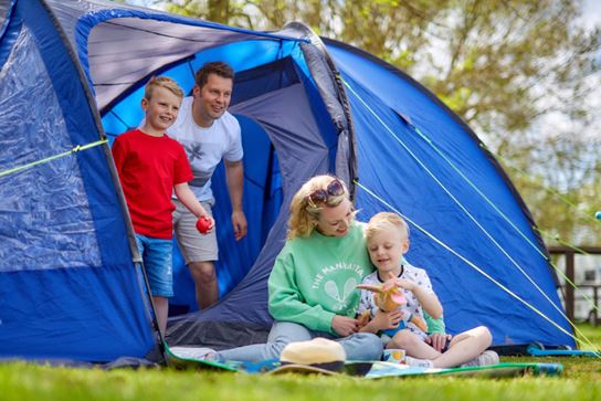 Family sat on the grass outside their tent