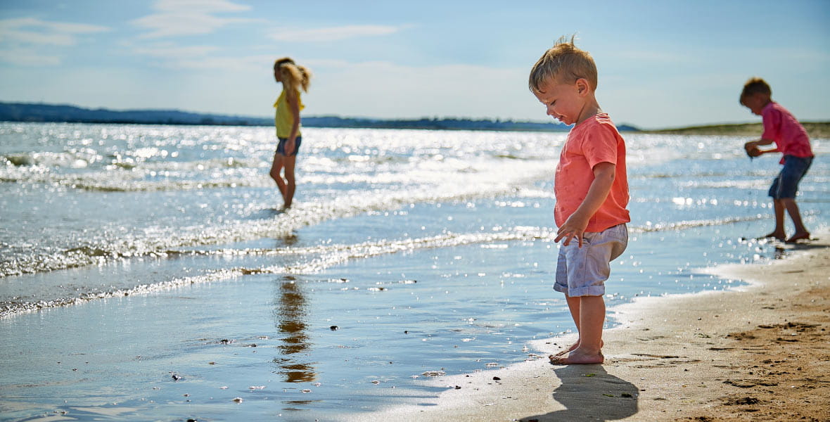 two kids walking into the sea on a sunny beach