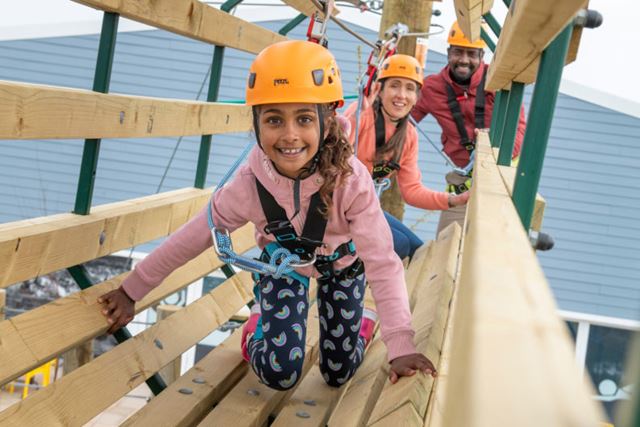 Little girl wearing yellow helmet on the high ropes