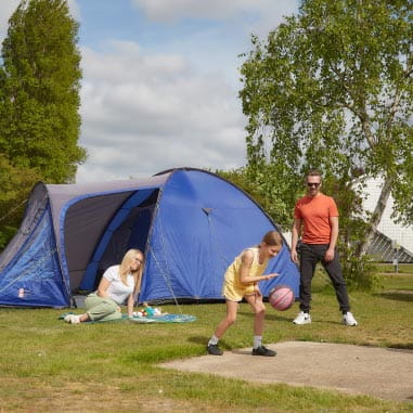 Family playing football outside a tent